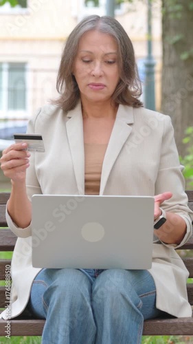 Old Senior Woman Upset with Online Banking Problems via Credit Card in Park