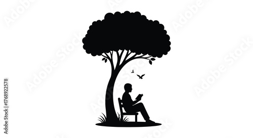 A person sits in a chair under a large tree reading a book with birds flying nearby silhouette