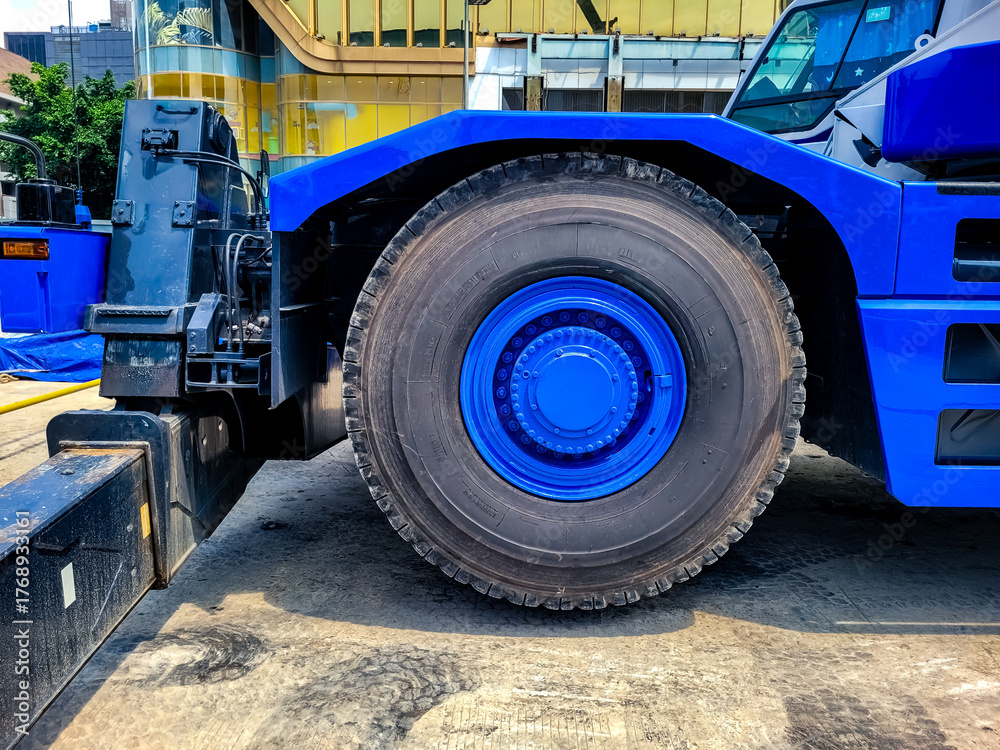 Fototapeta premium Close-up of a large blue construction vehicle wheel on a jobsite, highlighting heavy-duty machinery, strength, and industrial equipment in use.