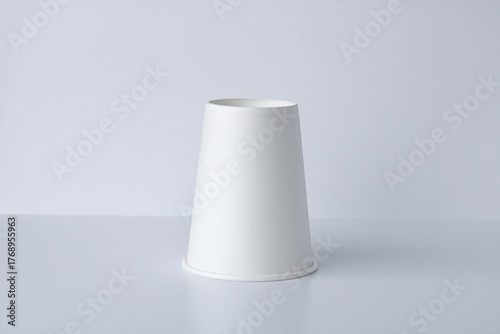 Cuadro en lienzo One white, cone-shaped paper cup is arranged upside down on a clean, white background