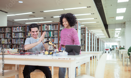 A teacher guiding students in a robotics project during a STEM class in the library