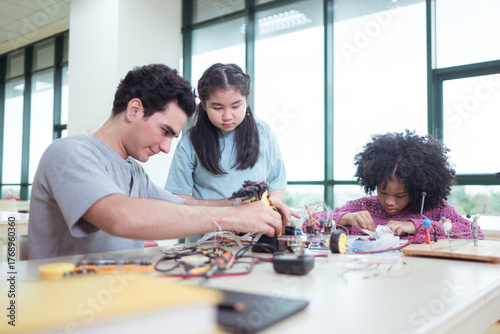 A teacher guiding students in a robotics project during a STEM class in the library
