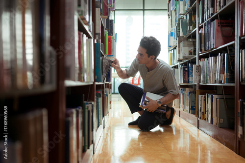 A young man stands between the shelves of a library