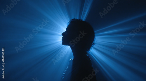 A silhouette of a person emanating a blue light in thought. The person is deep in thought and the rays are shining around the figure