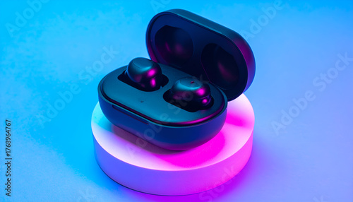Modern black wireless earbuds in an open charging case on a white pedestal with dramatic blue and pink lighting.
