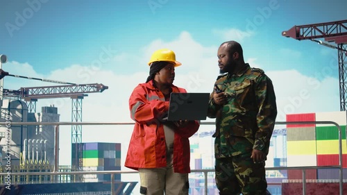 Soldier working on offshore platform transmitting security report with walkie talkie. Military unit boarding drilling barge under maritime interdiction protocol coordinates defense operation, camera A