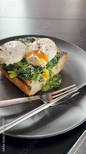 Poached egg is cut with a knife on whole grain toast with creamy spinach. Breakfast, lunch, dinner