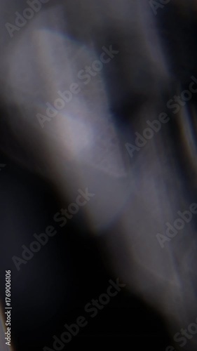 Vertical video. Blur visual dazzle. Art glow. Defocused lens flare flicker blue yellow spectrum texture floating on abstract dark black bokeh light background.
