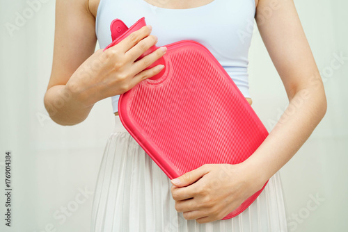 Woman using hot water bottle to relieve menstrual abdominal pain.
