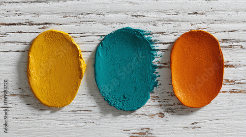 Vibrant color swatches of yellow, teal, and orange, on a rustic wood surface. These shades are artistically displayed, creating an appealing visual palette