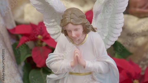 Catholic nativity scene with angels. Christmas religious still life with red flowers prayer and faith detail closeup
