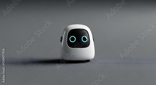 Compact white robot with glowing blue eyes and black faceplate standing on gray surface in sleek minimalist futuristic setting