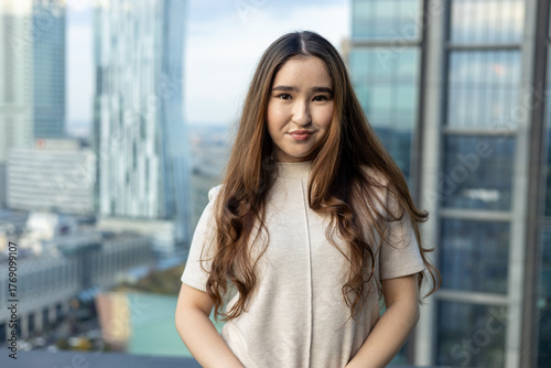 Asian woman in chic beige dress holding a handbag on a rooftop terrace with city skyline — full-length fashion & lifestyle portrait Free Download Asian woman in chic beige dress holding a handbag on a rooftop terrace with city skyline — full-length fashion & lifestyle portrait - GFXLoad