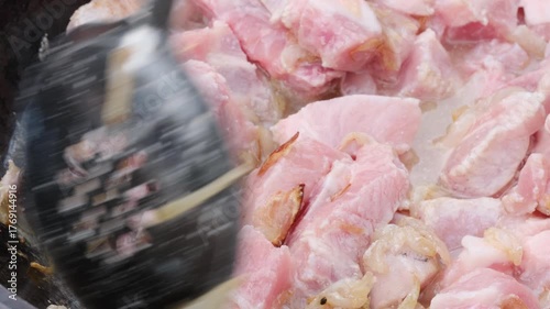 chopped onions and meat are fried in oil in a cauldron