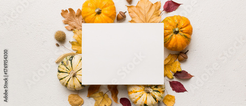 Autumn composition with paper blank and dried leaves with pumpkin on table. Flat lay, top view, copy space
