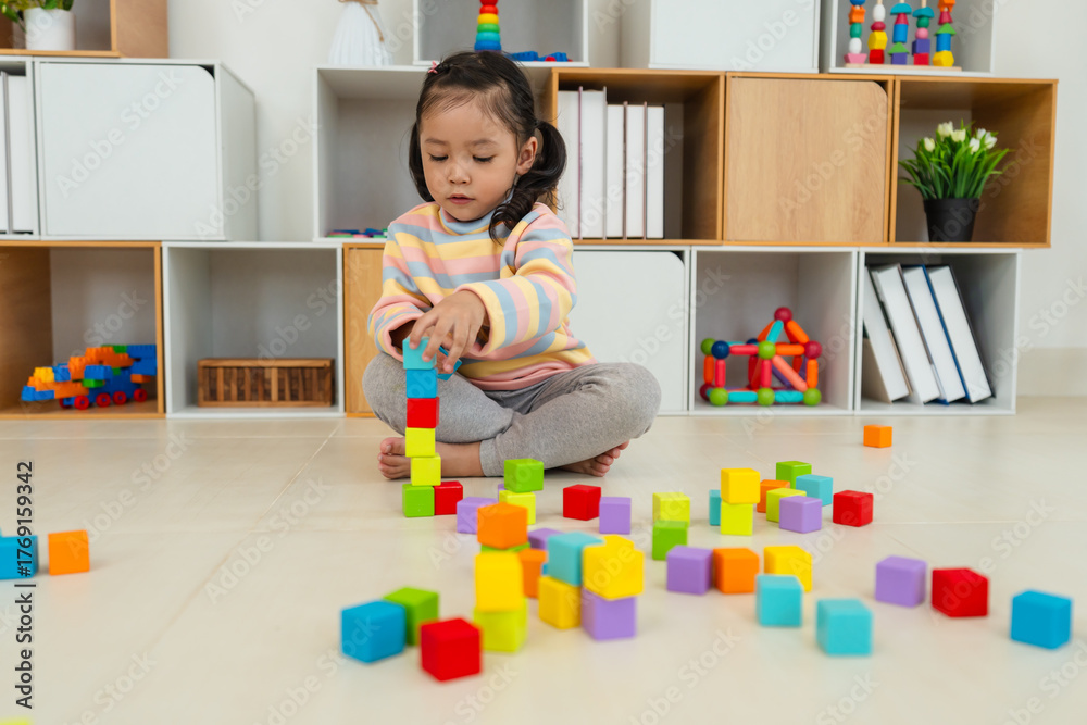 Fototapeta premium toddler girl playing block toy to stacks building cubes at home