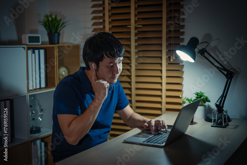 happy young man using wireless earbuds to listening music and laptop at night