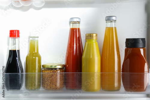 Φωτογραφία Bottles with different tasty sauces in fridge, closeup