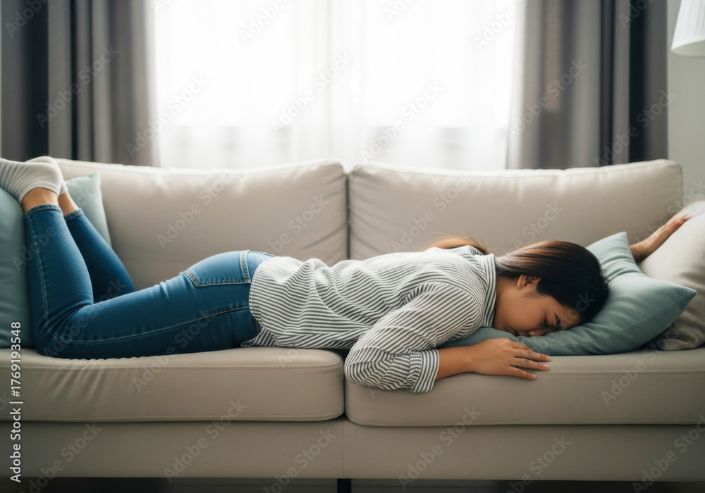 Obraz premium Exhausted Young Woman Lying Face Down on Couch at Home