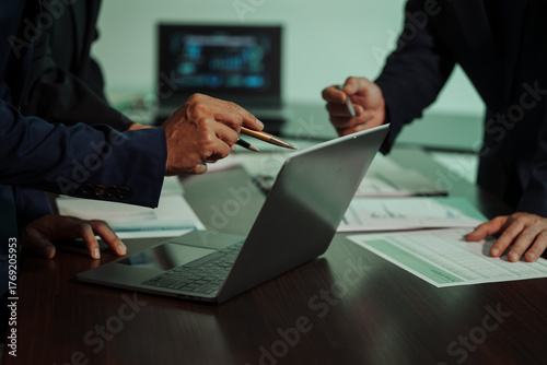 Business professionals closely review a balance sheet and digital Global Investment Portfolio data, pointing to key figures, indicating strategic financial planning and rigorous cash flow management.