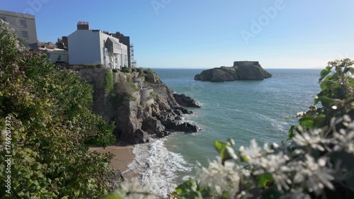 Tenby south beach at high tide with St Catherines Island in the distance on a bright sunny day.