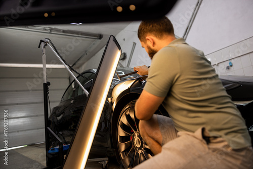 Worker Restoring Black Car Body Dents