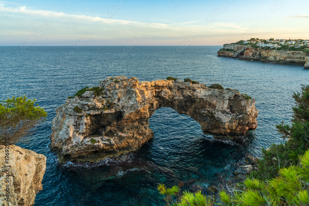 Φωτογραφία Natural stone arch in sea at Cala Santanyi, Mallorca, glowing in golden sunset light
