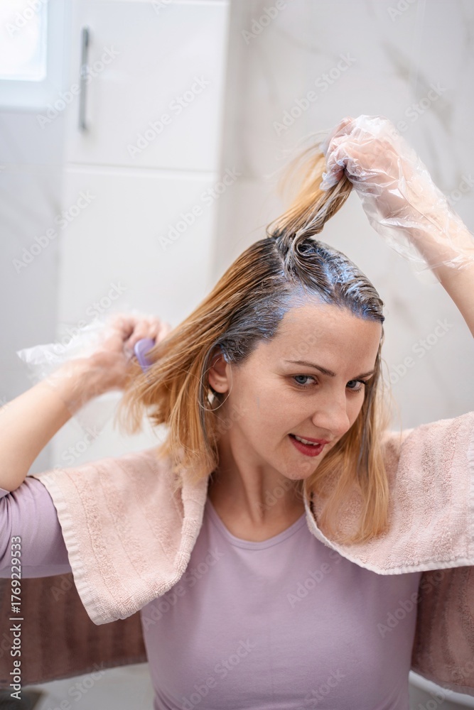Fototapeta premium Woman dyeing her hair at home in the bathroom