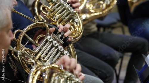 Musicians playing French horns in close-up of hands and instruments