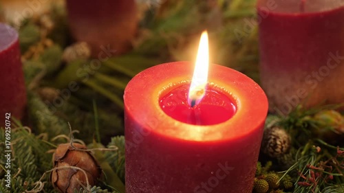 Lit red candle with pine cones and foliage, festive detail