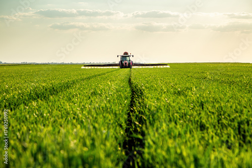 Tractor spraying crops in green agricultural field