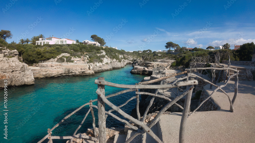 Naklejka premium A beautiful bbeach with a wooden fence surrounding it cala en brut menorca