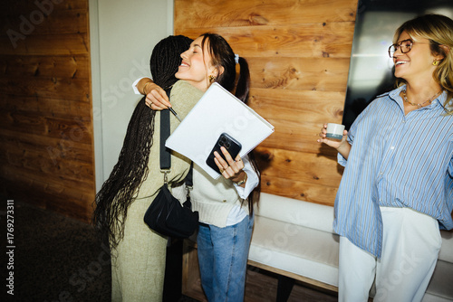 Colleagues greeting with hug in modern office