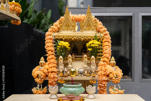 Gold Thai Spirit House with Offerings and Marigold Garlands in Bangkok, Thailand