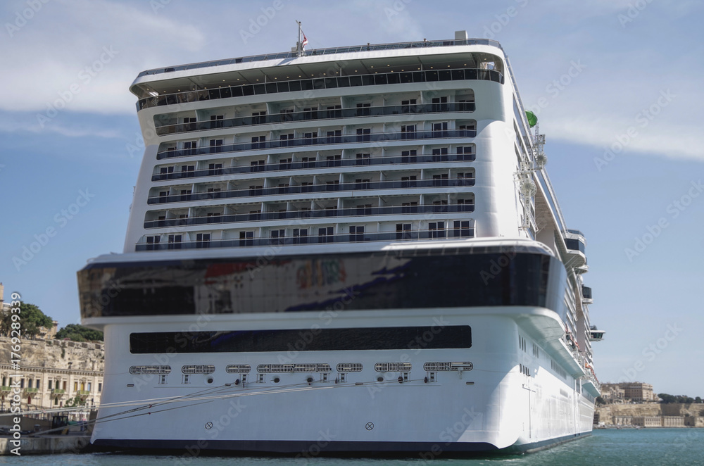 Naklejka premium Massive mega Italian family cruiseship cruise ship Grandiosa, Bellissima Meraviglia in Valletta during Summer Mediterranean cruising in sleek modern design with port infrasctructure and marine traffic