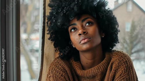 Pensive young woman gazes out window, lost in thought. Cozy, introspective mood.