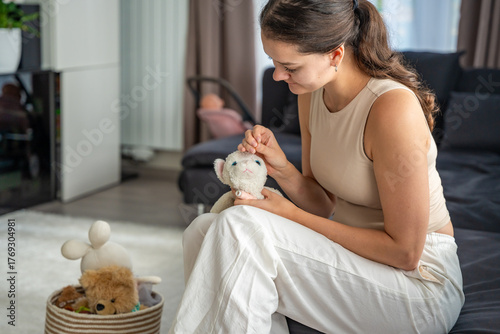 Vászonkép Young woman sewing an old plush toy at home with needle and thread