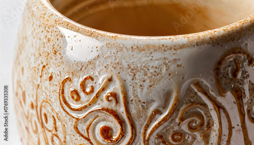 This close-up photo features a beautifully crafted ceramic pot with intricate designs. The warm earthy tones and glossy finish enhance its artistic elegance, making it a charming decor item for any sp