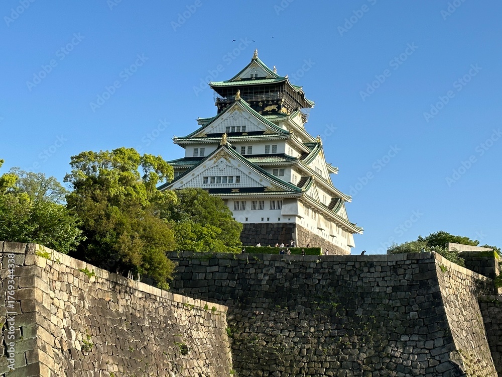 Fototapeta premium Historic Japanese castle with stone walls under blue sky