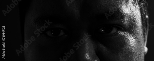 Canvas Print Dark moody portrait capturing both eyes under harsh lighting, conveying tension, seriousness, and emotional strength in fine art monochrome