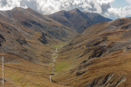 River between brown mountains and clouds in a blue sky