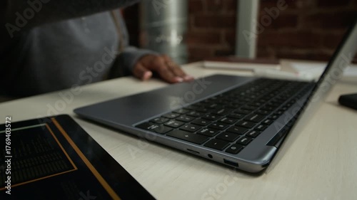 Cropped close up shot of hands of unrecognizable Black female developer sitting at office desk and opening laptop starting workday