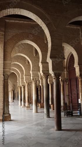 Corridor gallery around inner courtyard of Great Mosque of Kairouan in Tunisia with traditional Islamic arches and columns decorated with Corinthian capitals 