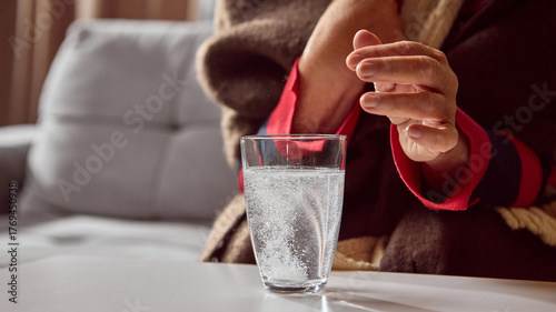 Elderly woman watching effervescent tablet dissolve in glass of water. Concept of pharmacy instruction, healthcare education, and wellness prevention.