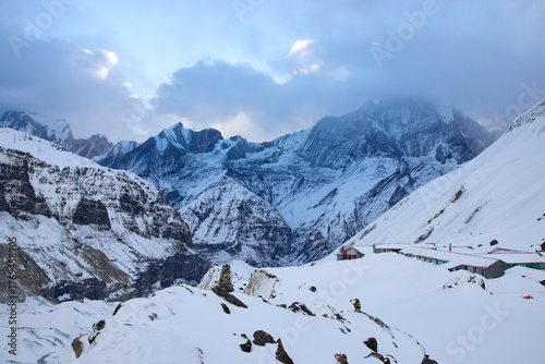 Mountains are covered with snow at Annapurna Base Camp. The sky is cloudy in the Himalayas, Nepal. It is winter in Annapurna Sanctuary