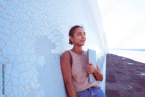 Young woman holding laptop looking at the horizon