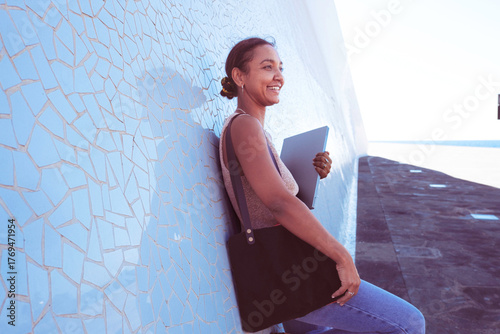 Woman smiling while working remotely with laptop outdoors