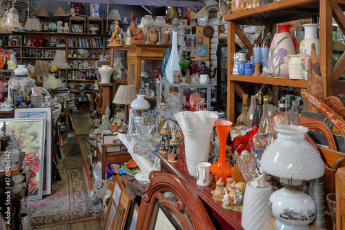 Large number of of multi colored antique, vintage, old, historic, knick knack, small collectables stacked on shelves and floor