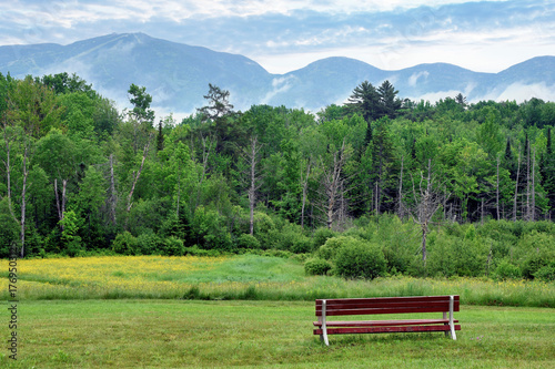 Inviting and relaxing springtime scene in White Mountains of New Hampshire. Scenic view of Cannon Mountain and Kinsman Range from wooden bench in village of Sugar Hill.