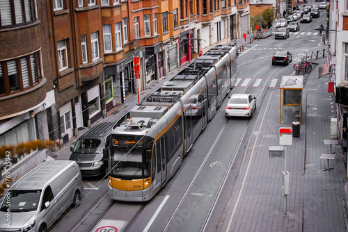 Top view of a European city street with tram tracks, modern tram, parked cars, brick buildings. Urban scene, city infrastructure, sustainable transport, streetscape, city life.